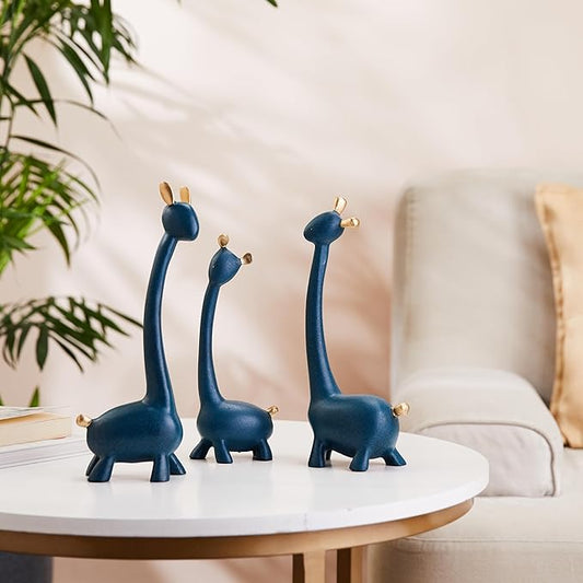 Three blue giraffe figurines on a white table with a blurred indoor background
