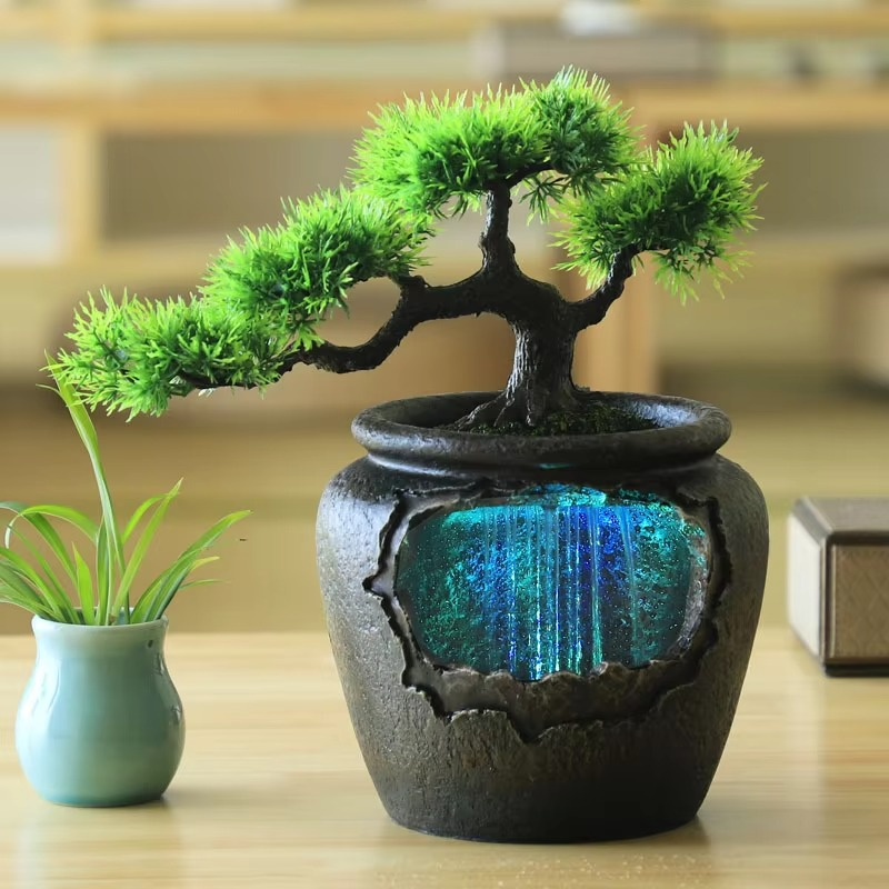 Bonsai tree in a decorative pot with a glowing blue interior on a wooden surface.