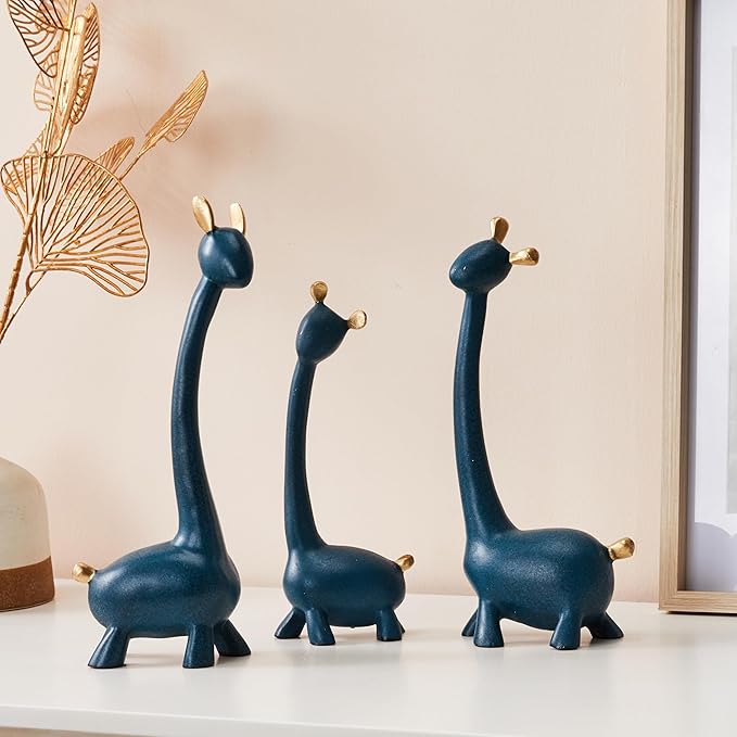 Three blue giraffe figurines on a white surface with a beige wall in the background.