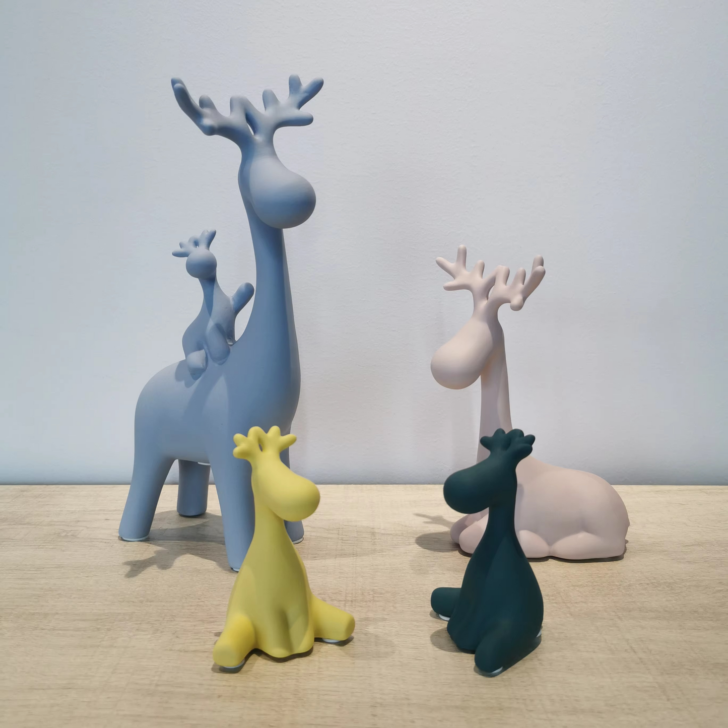 Set of colorful deer figurines on a wooden surface with a light gray background