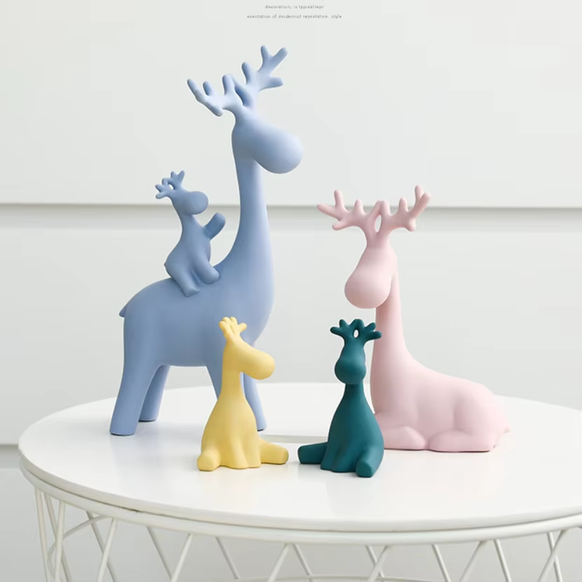 Set of colorful deer figurines on a white surface with a light gray background