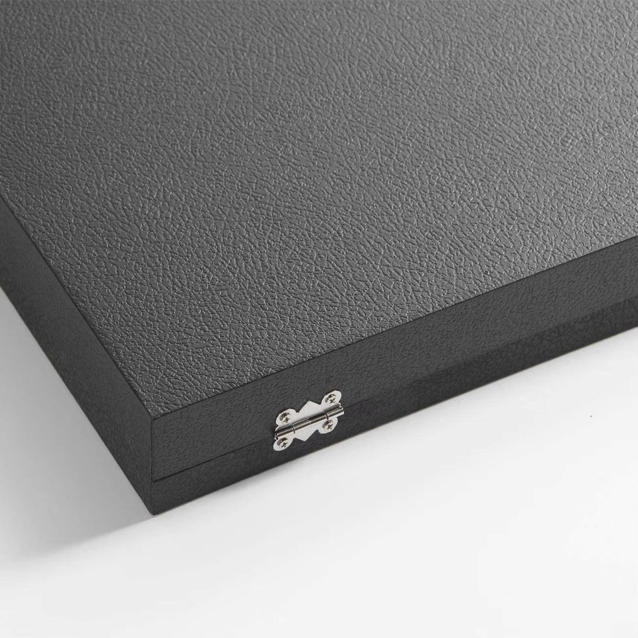 Close-up of a black leather-bound book with a visible brand logo on a white background