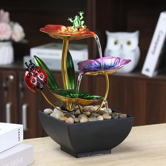 Colorful tabletop fountain with decorative elements on a wooden surface.