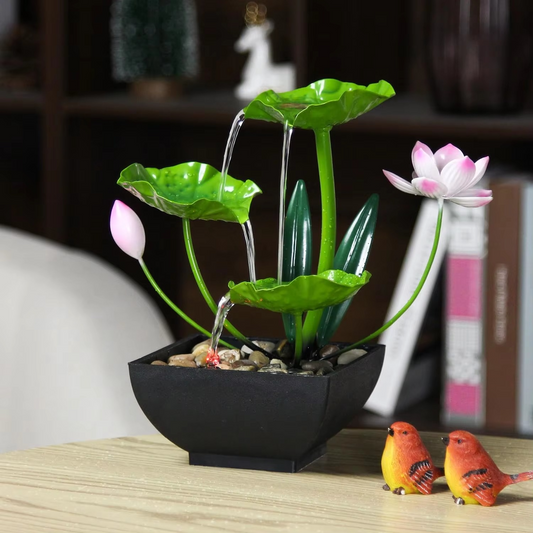 Decorative water fountain with lotus leaves and flowers on a table.