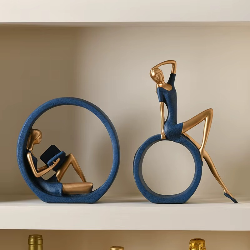 Two decorative statues of people on blue rings with a neutral background