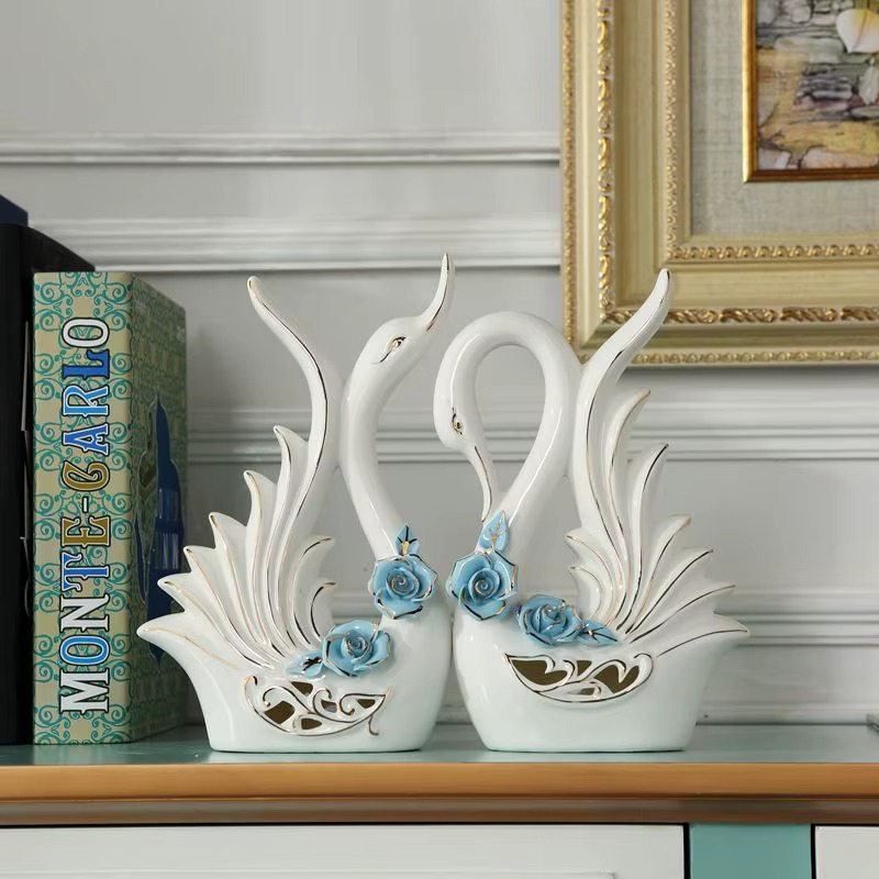Decorative swan figurines with blue flowers on a shelf.