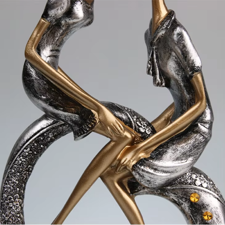 Decorative item with intertwined figures in gold and silver on a gray background