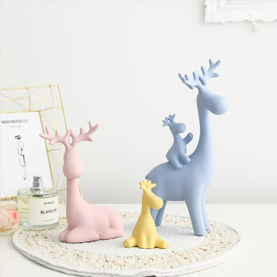 Decorative figurines of a pink and blue deer with a yellow giraffe on a textured surface.