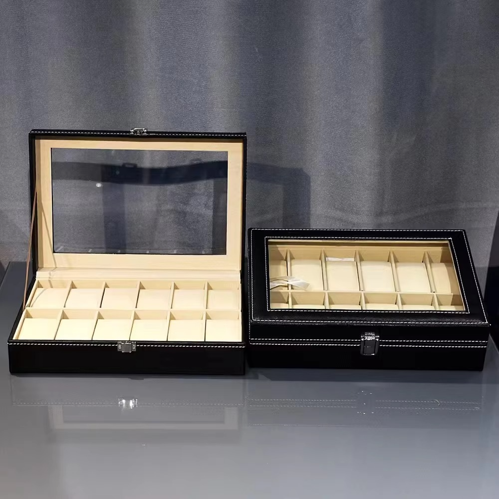 Two black jewelry boxes with glass lids on a gray surface.