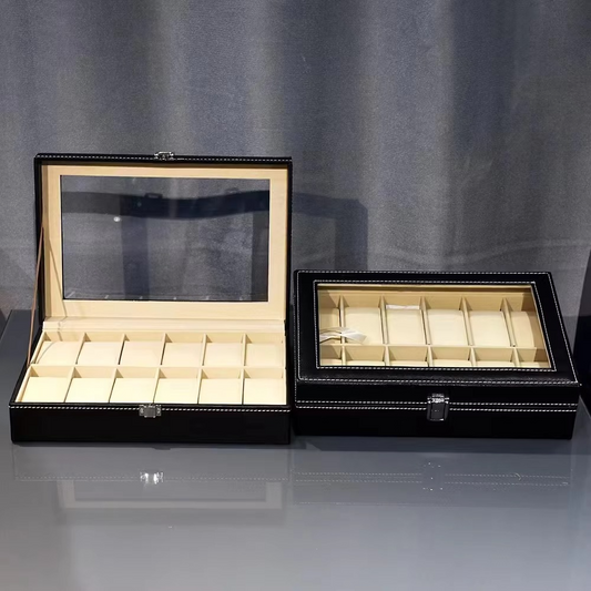 Two black jewelry boxes with glass lids on a gray surface.